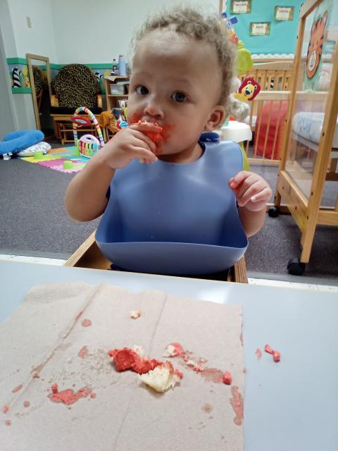 Infant enjoying a meal in a high chair at First School