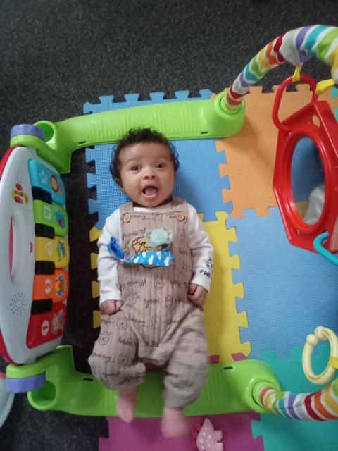 Infant playing on a colorful activity mat at First School